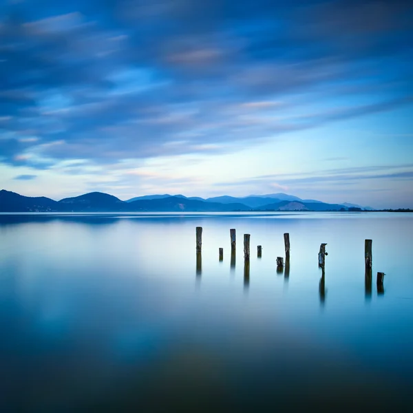 Träbrygga eller brygga finns kvar på en blå sjö solnedgång och sky reflektion över vatten. Versilia Toscana, Italien — Stockfoto