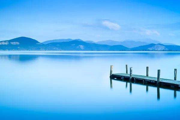 Muelle de madera o embarcadero y en un atardecer lago azul y reflectio cielo —  Fotos de Stock