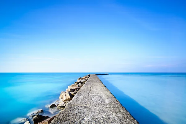 Béton et rochers jetée ou jetée sur l'eau bleue de l'océan — Photo