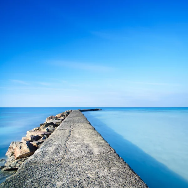 Beton i skały molo lub molo na niebieski ocean wody — Zdjęcie stockowe