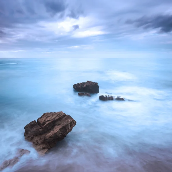 Horniny ve vlnách oceánu za zatažené obloze. špatné počasí. — Stock fotografie