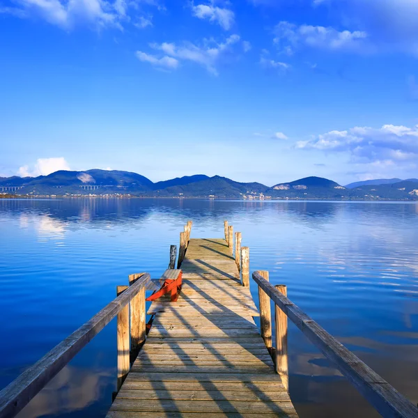 Holzsteg oder Steg auf einem blauen See Sonnenuntergang und Himmelsspiegelung auf — Stockfoto