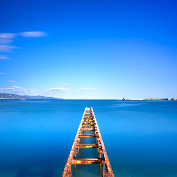 Muelle de madera o embarcadero permanece en un lago azul del océano. Exposición larga —  Fotos de Stock