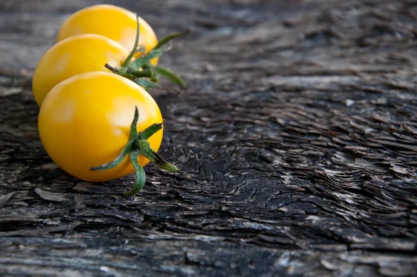 Žlutá rajčata na dřevěné pozadí — Stock fotografie