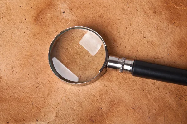 Magnifying glass on the old paper background — Stock Photo, Image