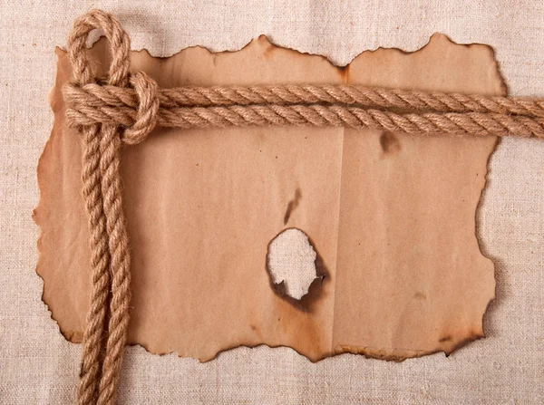 Knot and old paper on the background of old cloth — Stock Photo, Image
