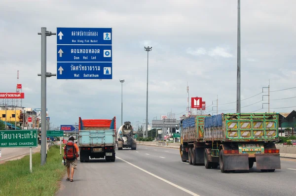 Backpacker with backpack walking on highway in Thailand — Stock Photo, Image