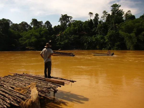 Man looks from timber pier to muddy river — Stock Photo, Image