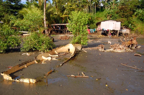 Barco abandonado perto da casa da aldeia na costa oceânica de maré baixa — Fotografia de Stock