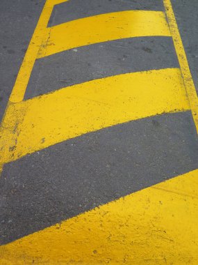 Siyah asfalt üzerinde sarı çizgili yol işaretleri var.