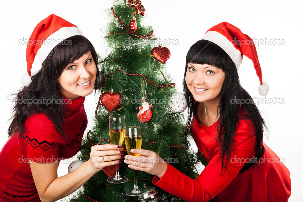Two girls with champagne near Christmas tree
