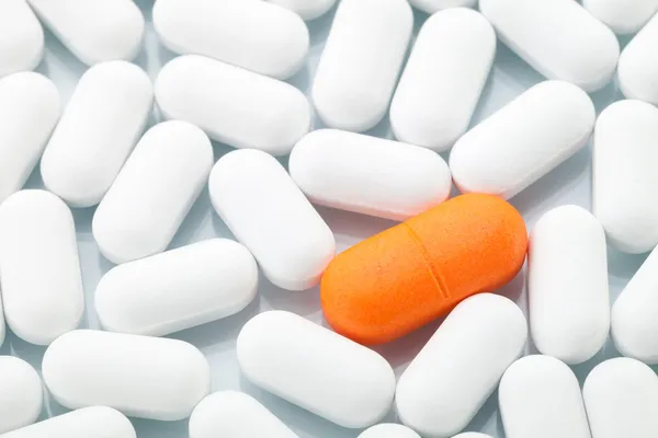 Orange pill between white ones Royalty Free Stock Images