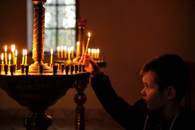 Küçük Çocuk kilise mumu yakıyor. Bir çocuk şapelde mum yakar.