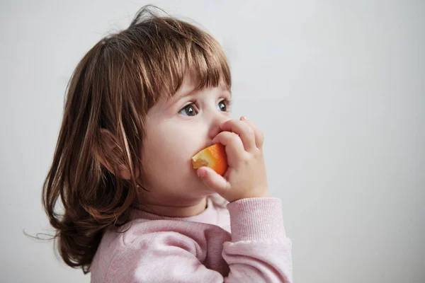 Adorable Niña Comiendo Una Rebanada Naranja Aislada Sobre Fondo Blanco — Foto de Stock