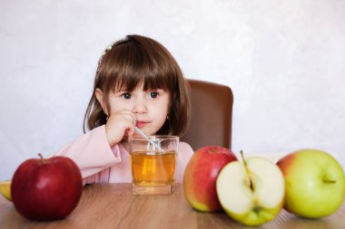 Şirin küçük kız pipet içerek elma suyu içiyor. Meyve suyu ve elmalı küçük kız. Sağlıklı yemek..