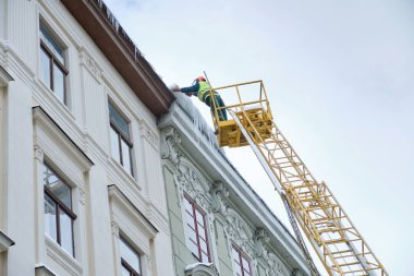 Özel araçlardaki kamu hizmetleri, Lviv 'deki Rynok Meydanı' ndaki evlerin çatısındaki sarkıtları kaldırıyor. Çatı Kışçıları. Çatıdan sarkan büyük buz sarkıtları