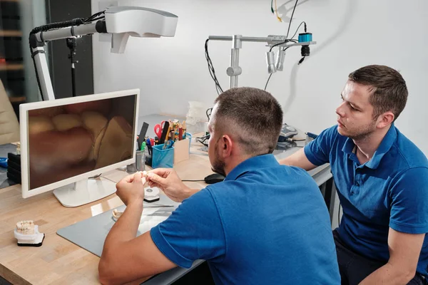 Dental technicians producing dental prosthesis under the microscope. The concept of prosthetics and implantology.