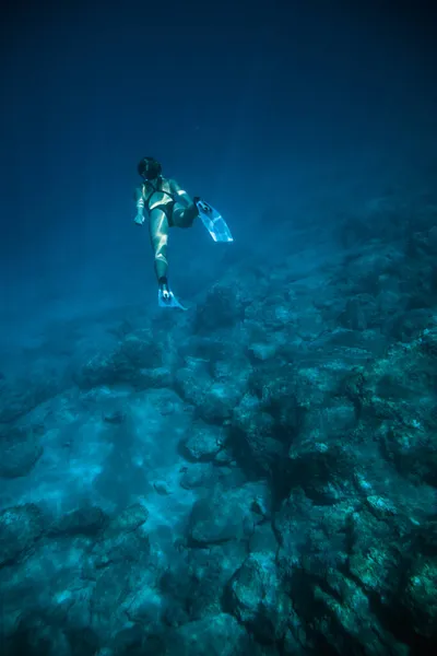 Chica de tiro submarino bucea bajo el agua libre en un traje de baño negro en agua clara — Foto de Stock