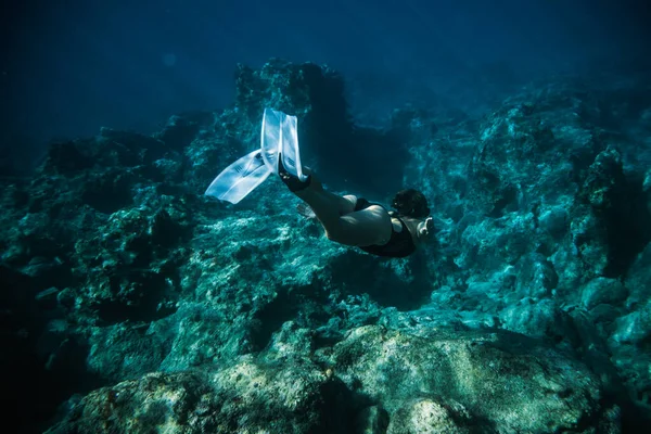 Underwater shooting girl dives underwater freediving in a black swimsuit in clear water — Stock Photo, Image