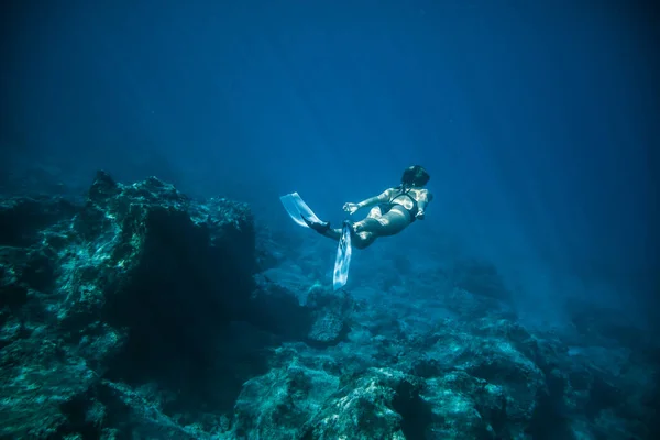 Chica de tiro submarino bucea bajo el agua libre en un traje de baño negro en agua clara — Foto de Stock