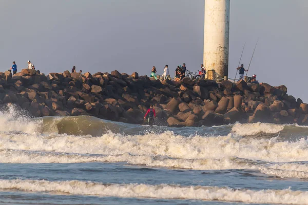 Farol platformunun önünde sörf yapan kişi