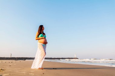 Hamile kadın üstte ve etekli Beac 'te karnını okşuyor
