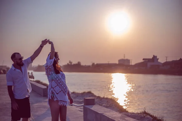 Hamile çift gün batımında platformda dans ediyor.