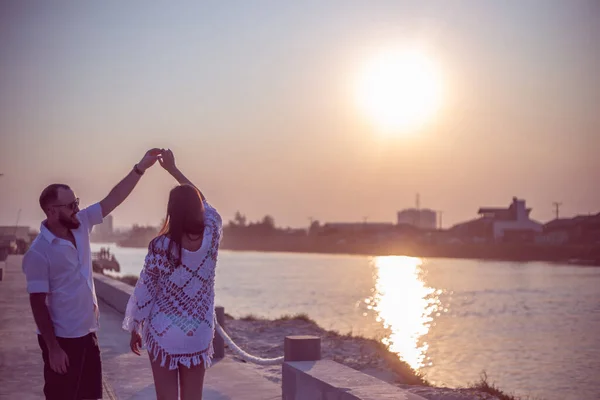 Hamile çift gün batımında platformda dans ediyor.