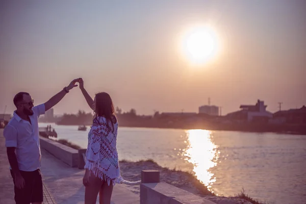 Hamile çift gün batımında platformda dans ediyor.