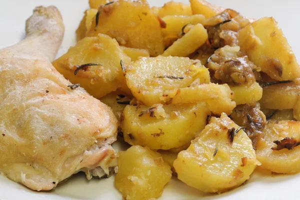 Patate al forno e coscia di pollo su un piatto Immagine Stock