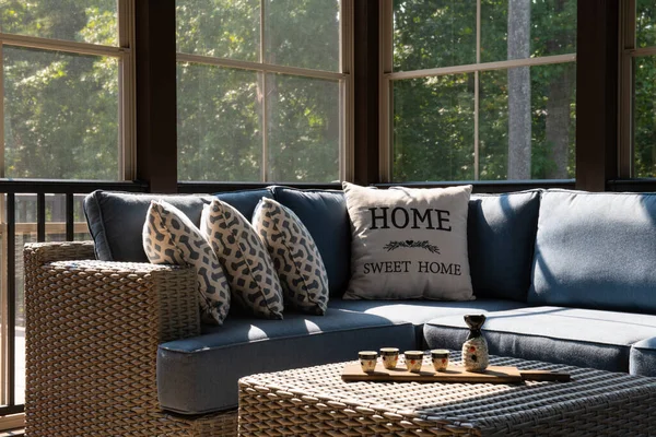 モダンなポーチの窓 パティオの家具 クッション 枕付きの屋外リビングスペースの居心地の良いコーナー コーヒーテーブルの上のセラミック酒セットとカップ 背景の森 — ストック写真