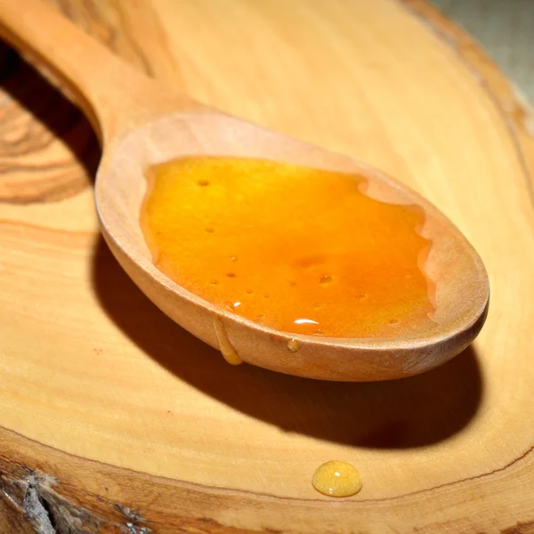 Golden honey i trä sked — Stockfoto