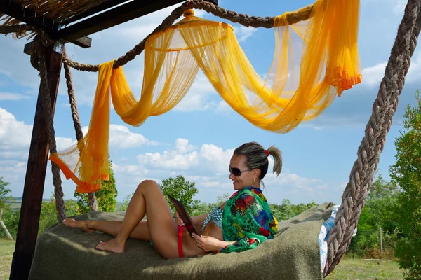 Jovem mulher relaxante em rede com tablet — Fotografia de Stock