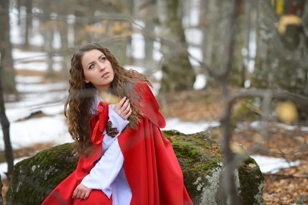 Mulher bonita com manto vermelho posando na floresta — Fotografia de Stock