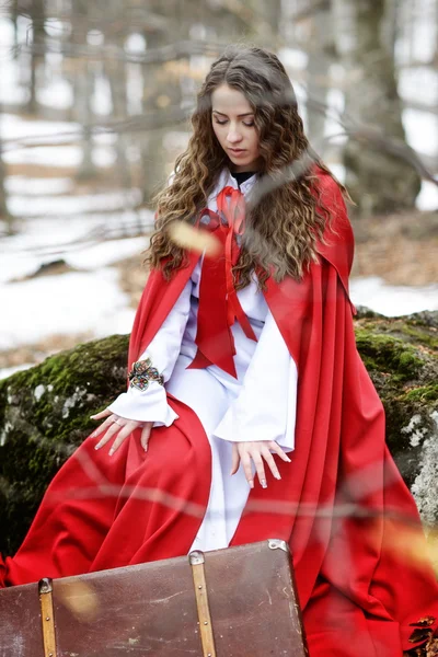 Beautiful woman with red cloak and suitcase — Stock Photo, Image