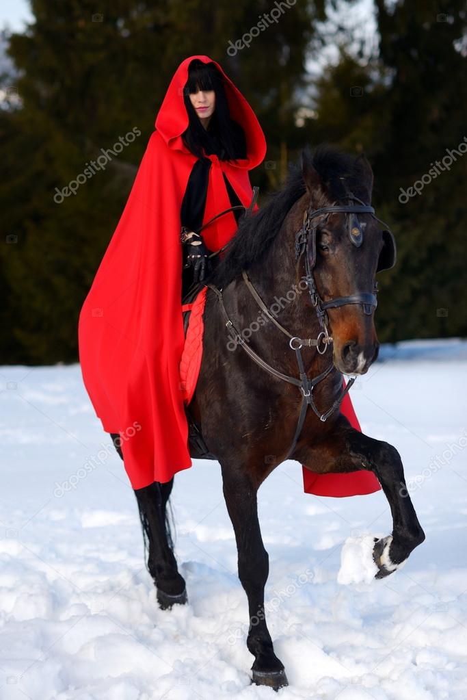 Beautiful woman with red cloak with horse outdoor in winter