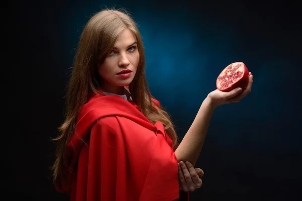 Mooie vrouw met rode mantel houden granaatappel — Stockfoto