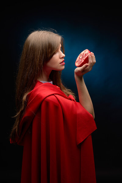 beautiful woman with red cloak holding pomegranate
