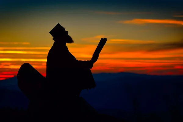 Silhouette di prete che legge alla luce del tramonto — Foto Stock