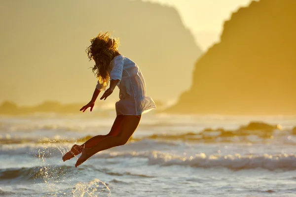 Jonge vrouw springen op het strand in de zomer — Stockfoto