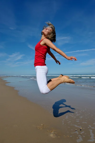 Young woman jumping on the beach in summer — Stock Photo, Image