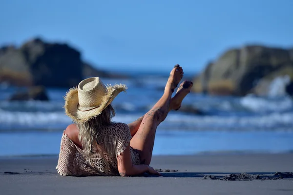 Νεαρή γυναίκα χαλαρώνοντας στην παραλία το καλοκαίρι — Φωτογραφία Αρχείου