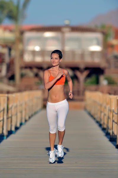 Junge Frau joggt am Strand — Stockfoto