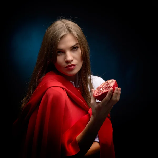 Bela mulher com manto vermelho segurando romã no estúdio — Fotografia de Stock