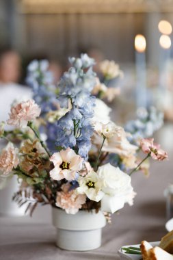 Düğün dekorasyonu masa dekorasyonunda. Bir buket beyaz çiçek, mumlu bir kompozisyon..