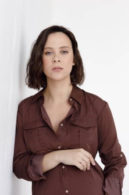 Hamilelik, geçmişi boş bir stüdyo. Beyaz arka planda bordo bir elbise giymiş güzel hamile bir kadın..