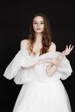 Gelinlik giymiş bir gelin, mutlu bir gülümseme ve bir portre. Siyah arka planda beyaz elbiseli çekici bir kadının portresi..