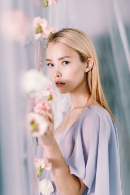 Beyaz ve pembe çiçekli güzel bir kadının portresi. Polietilen ile bahar moda fotoğrafçılığı.