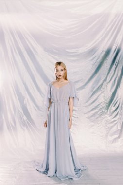 Arka planda çiçekler olan polietilen giymiş güzel bir kızın portresi. Moda portresi, çevre gündemi.