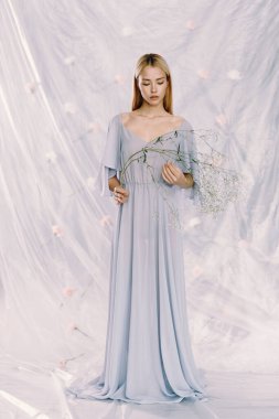 Arka planda çiçekler olan polietilen giymiş güzel bir kızın portresi. Moda portresi, çevre gündemi.